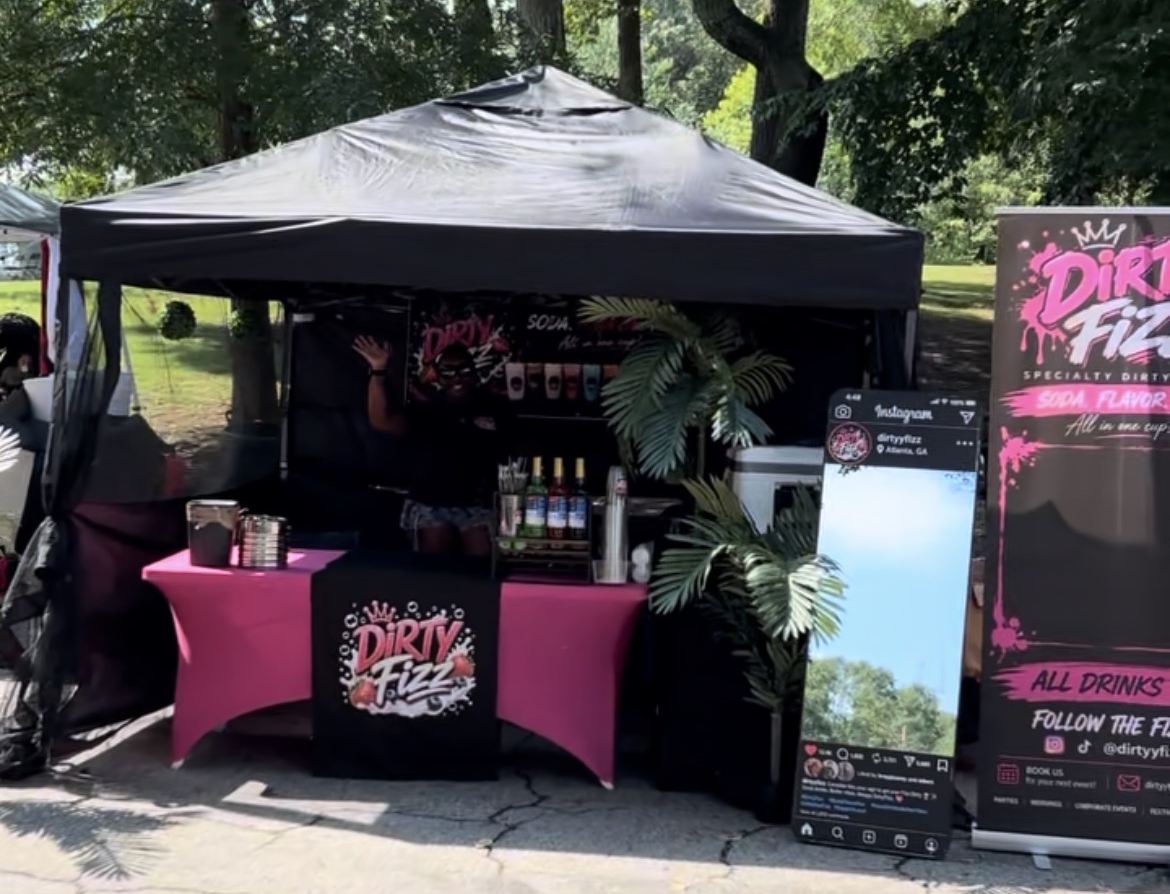 Dirty Fizz pop-up bar under the trees with pink tables, syrups and palm plants